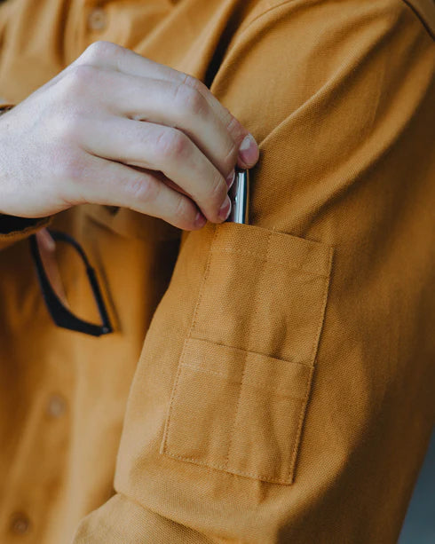 Close-up of a hand using the pencil pocket on MEN'S LONG SLEEVE WORK SHIRT (Camel) | DIXXON, showcasing its practical design.