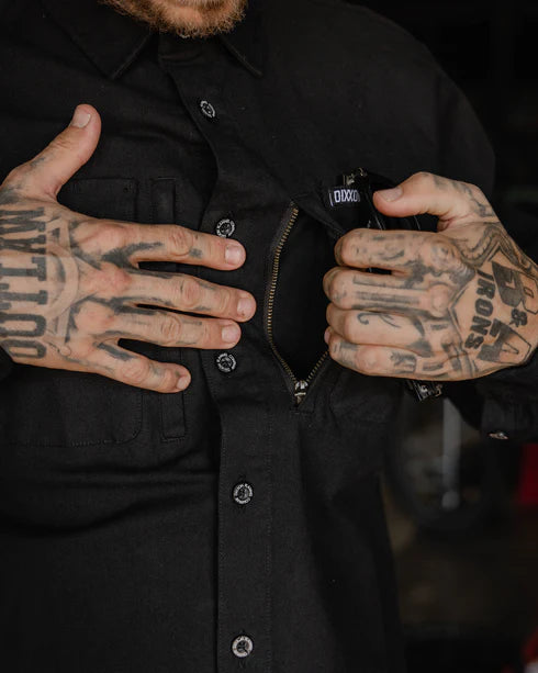 Close-up of a man's hands unzipping the pocket of a MEN'S LONG SLEEVE WORKSHIRT (Black) | DIXXON, showcasing its practical design.