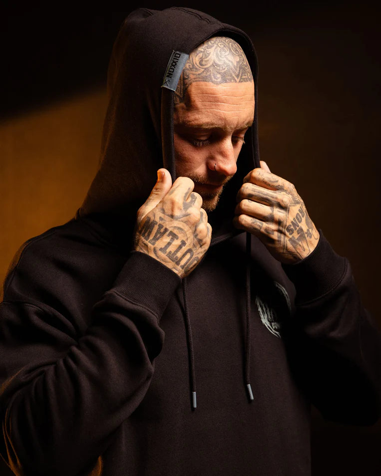 MEN'S WITCHING HOUR HOODIE (Black/Blue) | DIXXON model wearing hoodie with tattooed hands, adjusting drawstring hood.